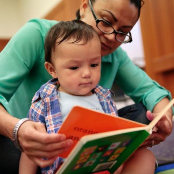 A teacher reads a book with a young child.